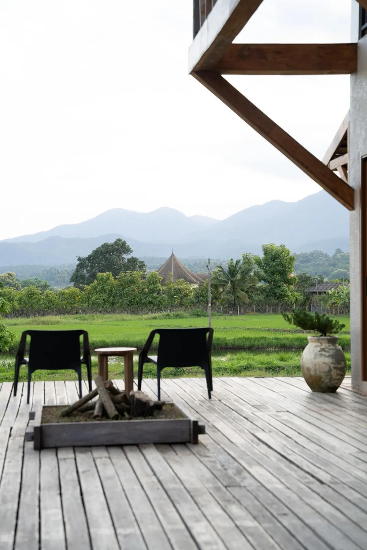 Wooden deck with two chairs and a fire pit facing the mountains